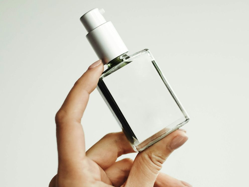 Hands holding a small glass vial of perfume