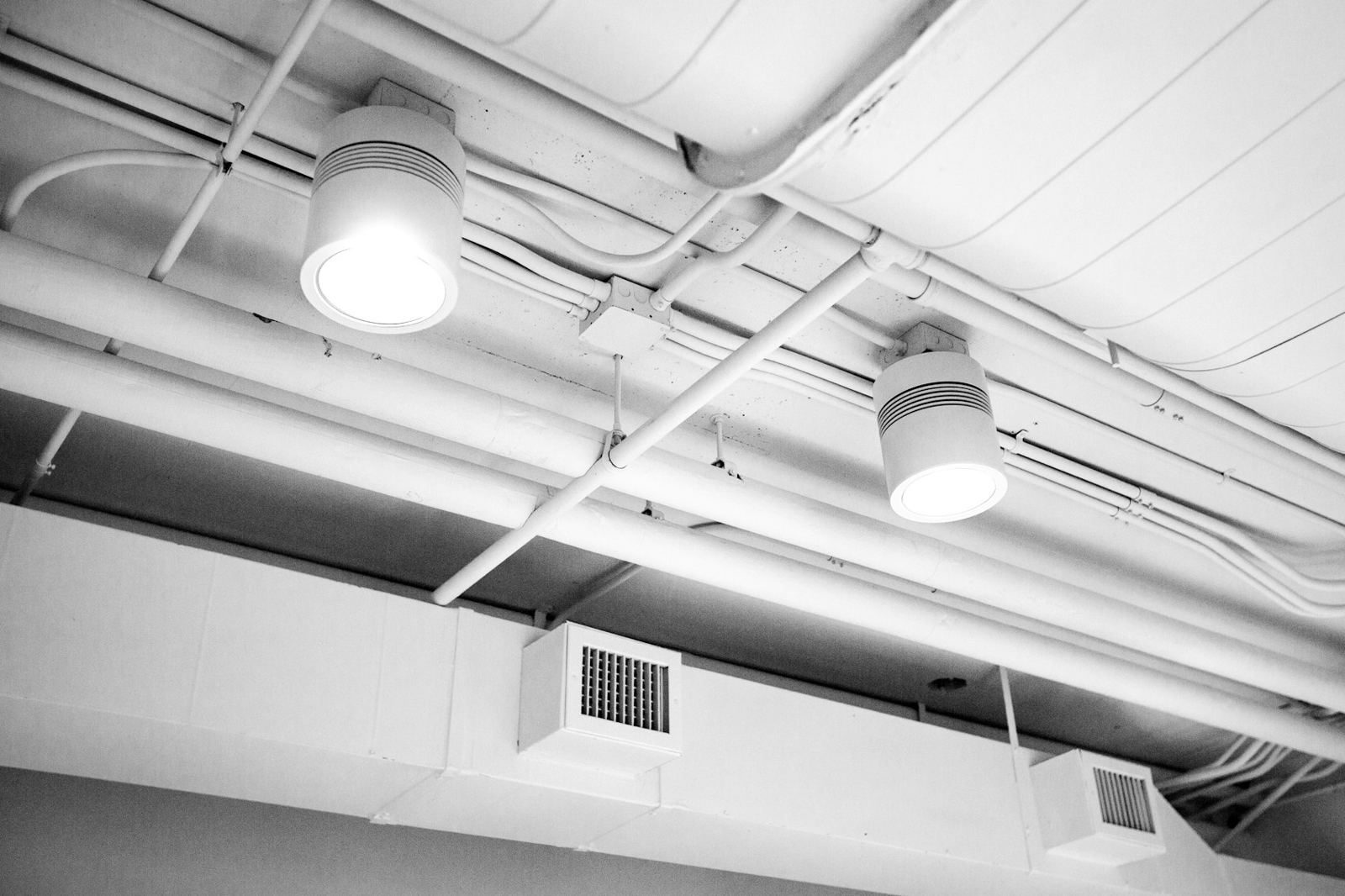 A ceiling with exposed ductwork and a supply register