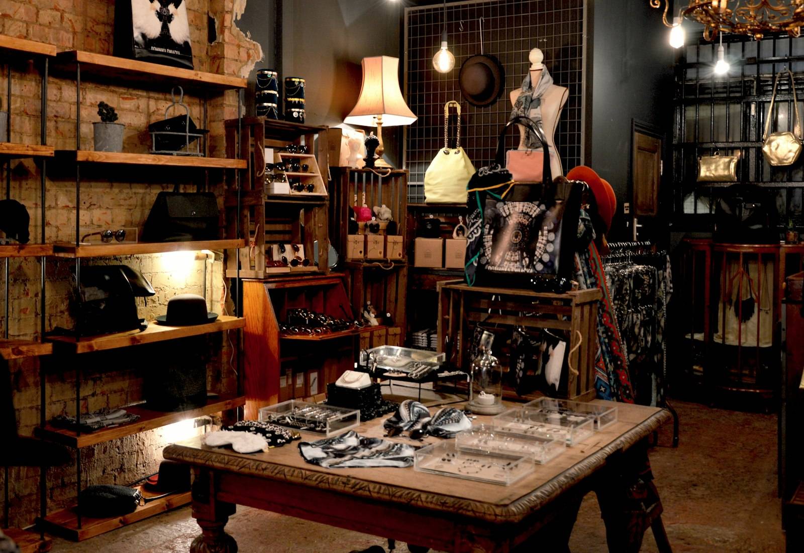 Inside a vintage shop with racks, lamps and a display table