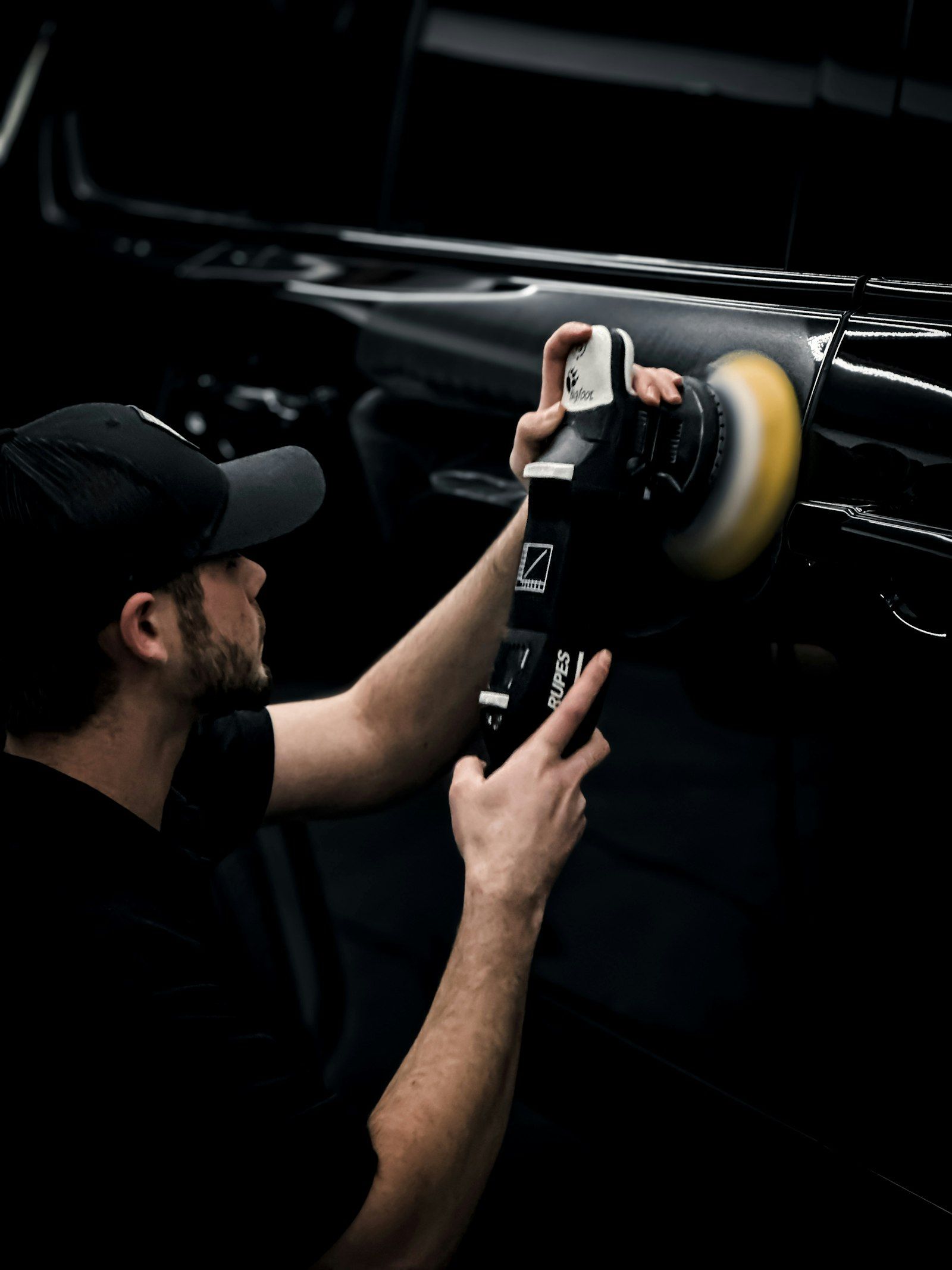 Technician polishing a car in a dark bay
