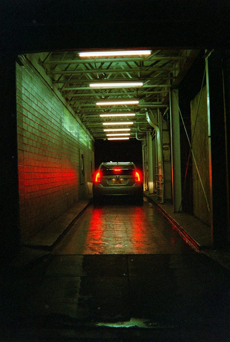 Car driving through a dark tunnel with red taillights