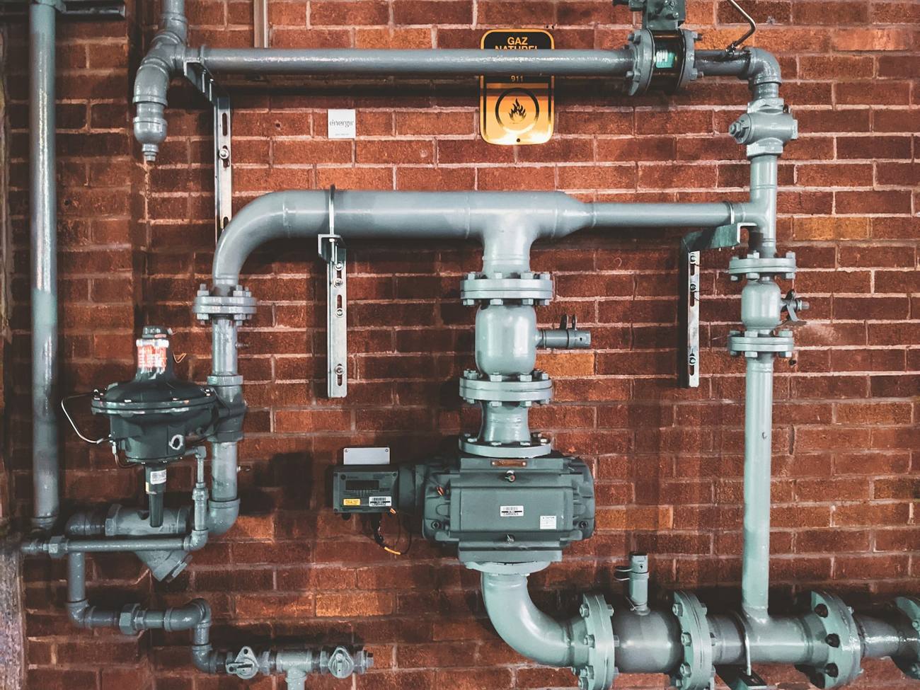 Steel pipes and valves on a brick wall