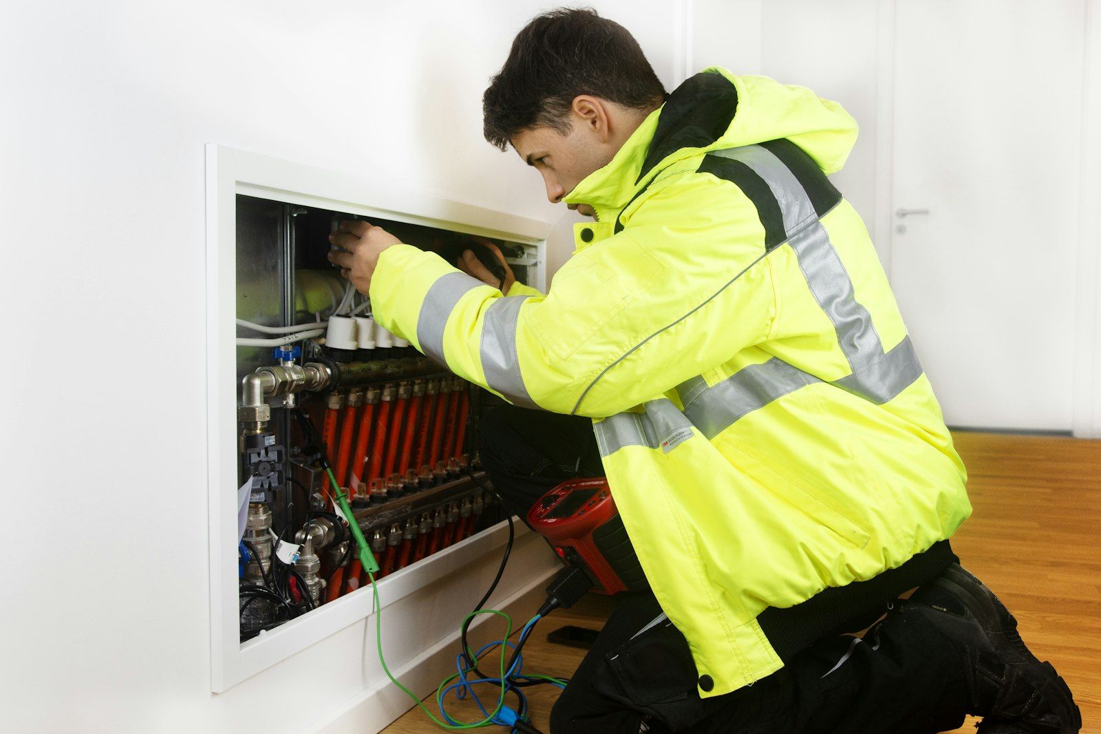 Technician in high-visibility jacket working on a control panel