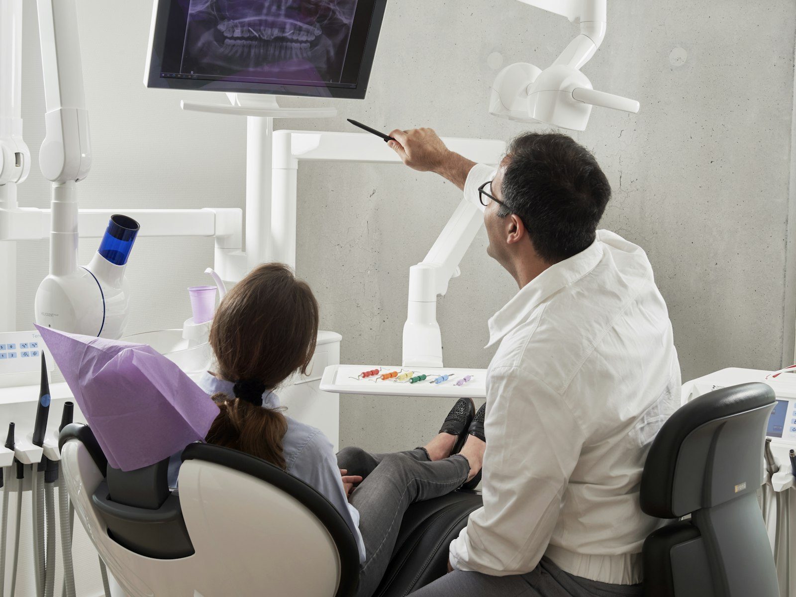 A dentist walking a patient through her X-rays on a screen