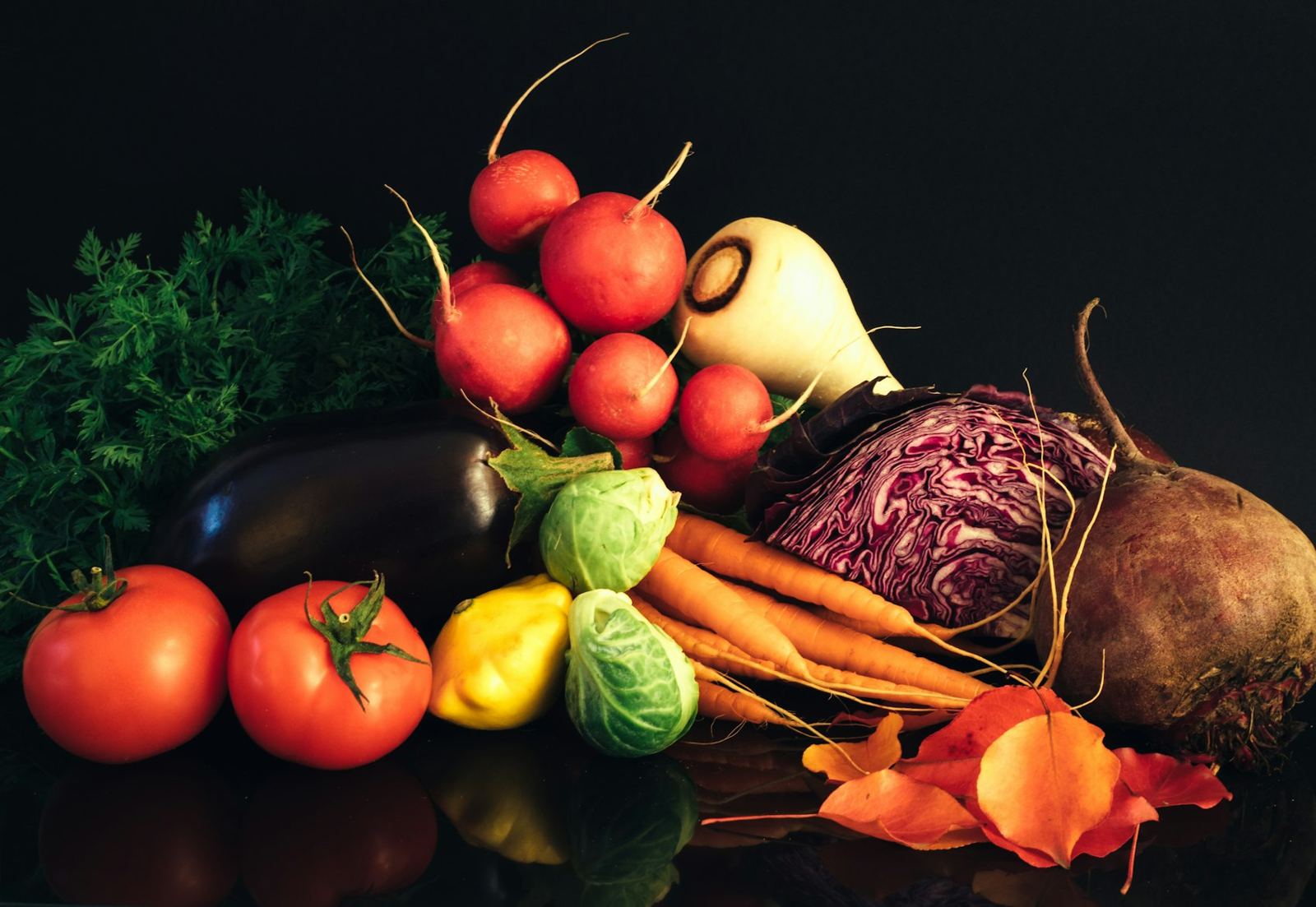 Radishes, beets, carrots and cabbage on a dark table