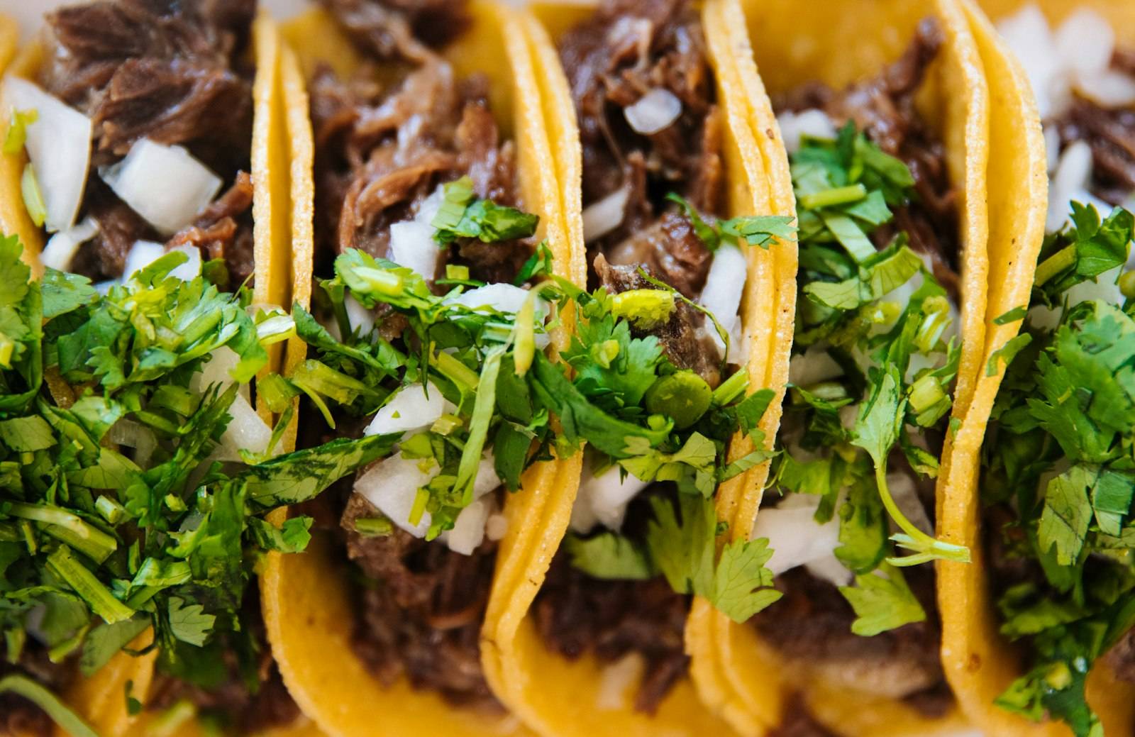 Three beef birria tacos with onion and cilantro