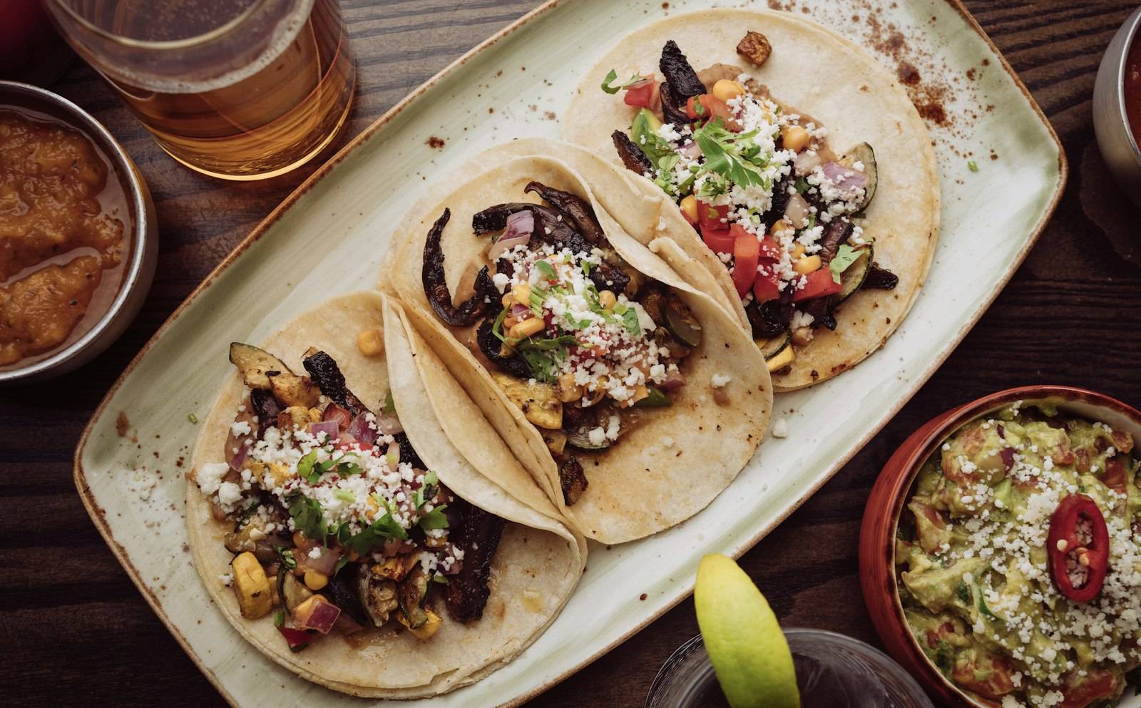 Plate of street tacos with salsa and a drink