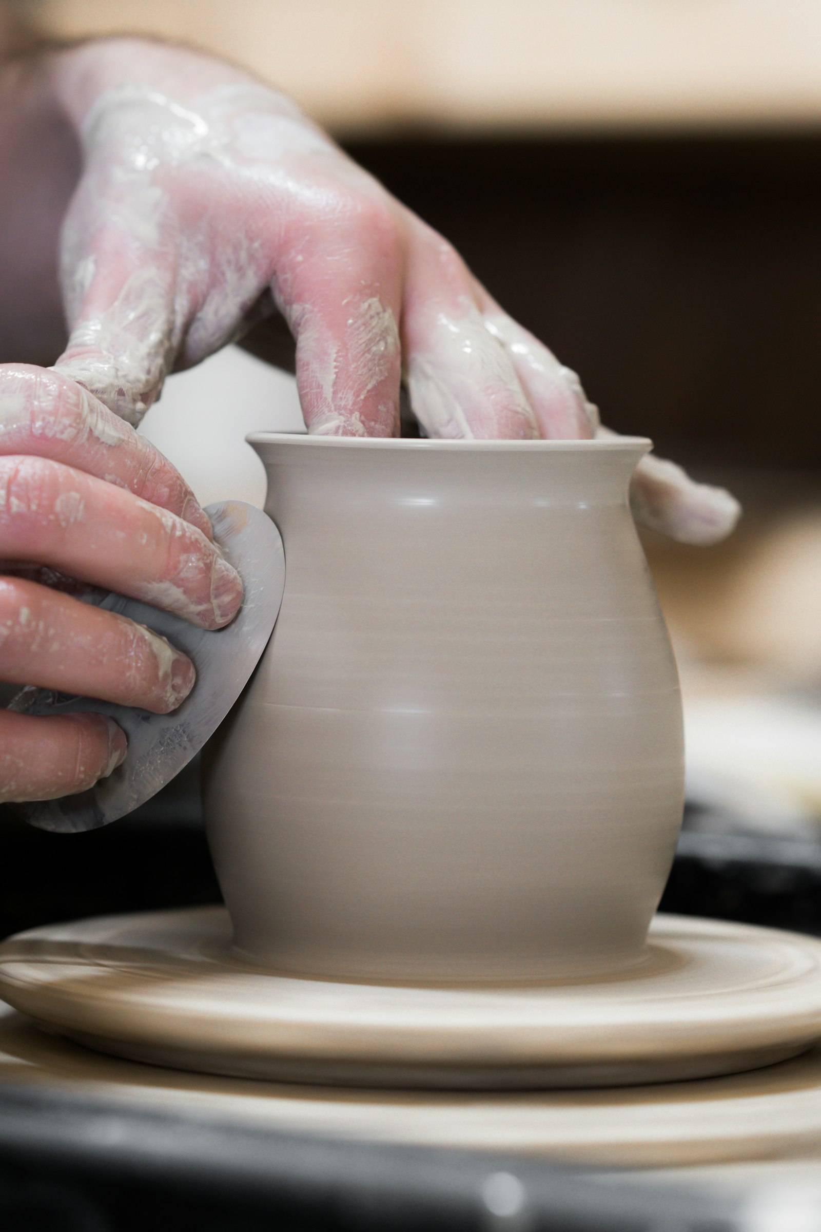 Hands shaping clay on a wheel