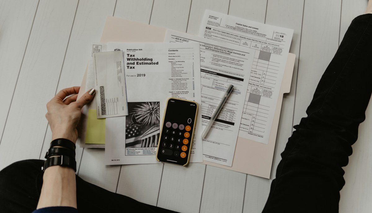 Person holding paper near pen and calculator