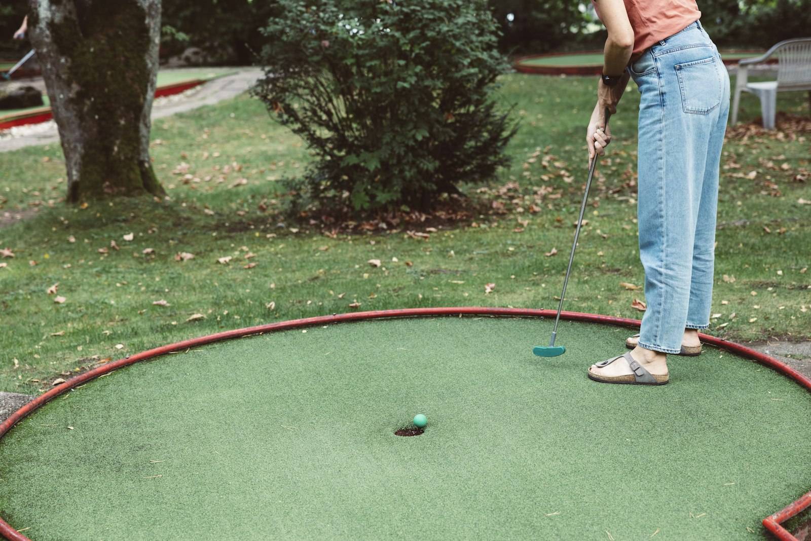 Player putting on a round mini golf green