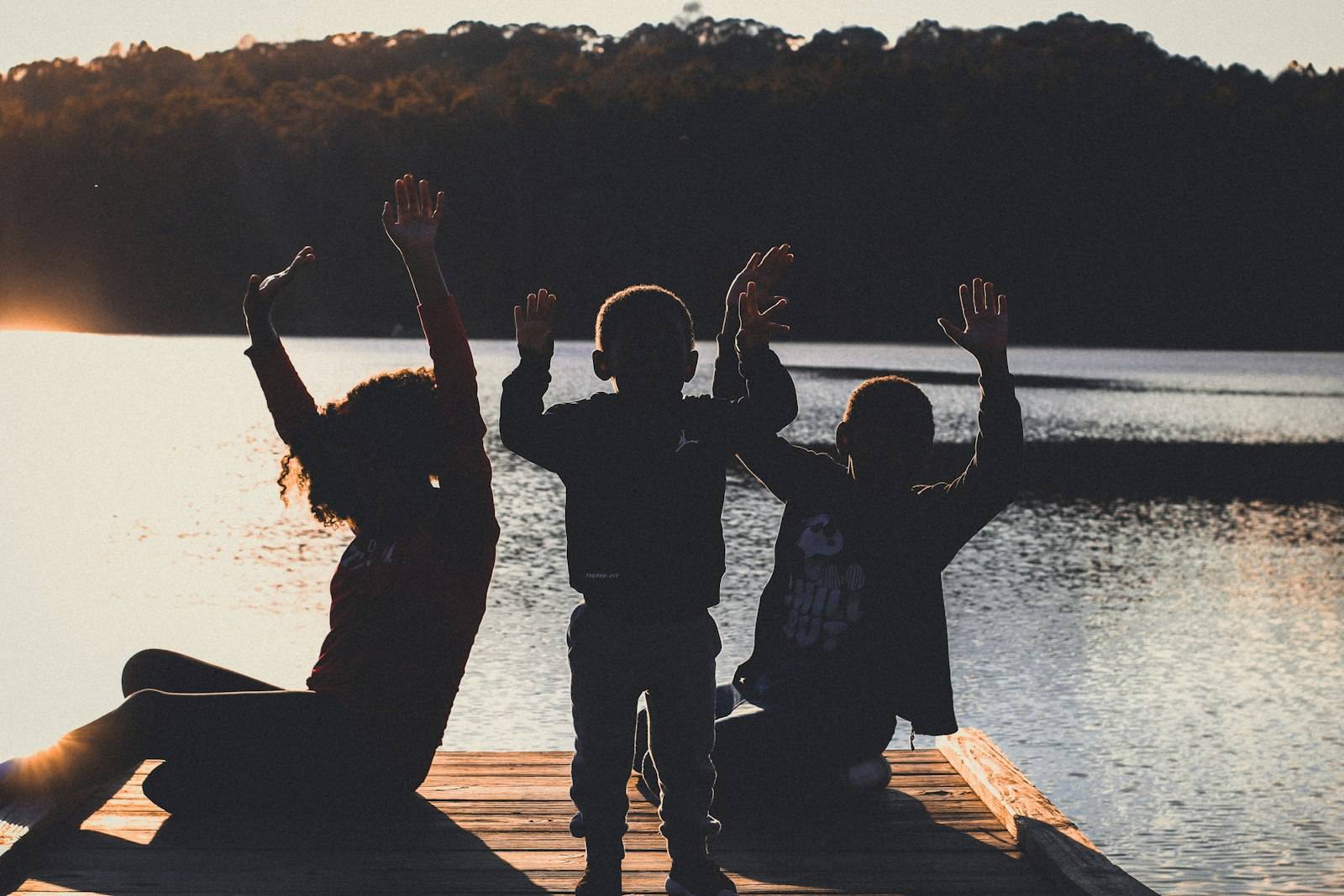 Family silhouettes by a lake at sunset