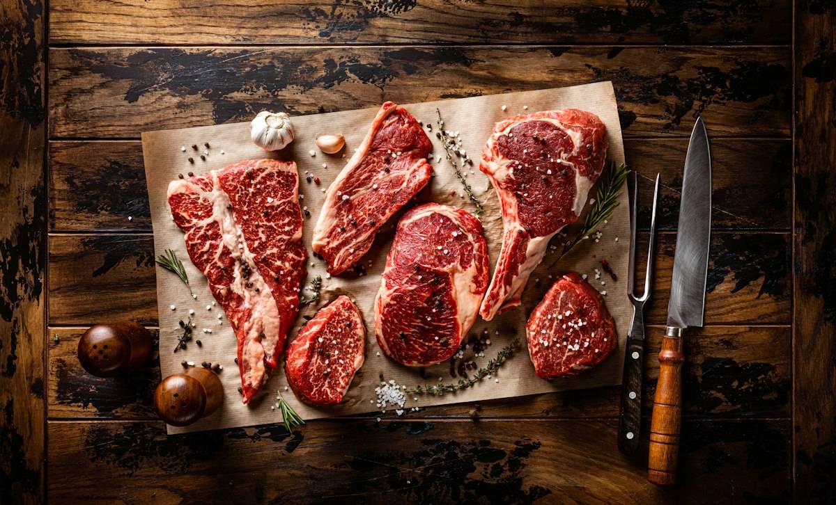 Raw meat on a cutting board next to a knife