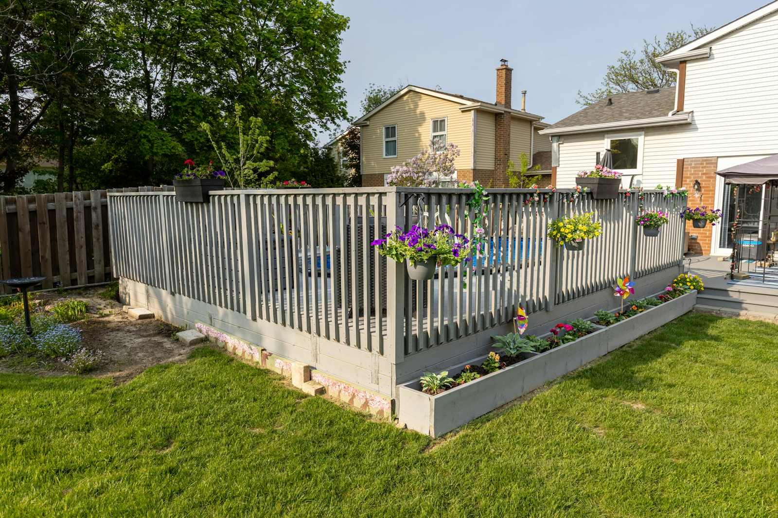 Grey railing fence with flower boxes around a lawn