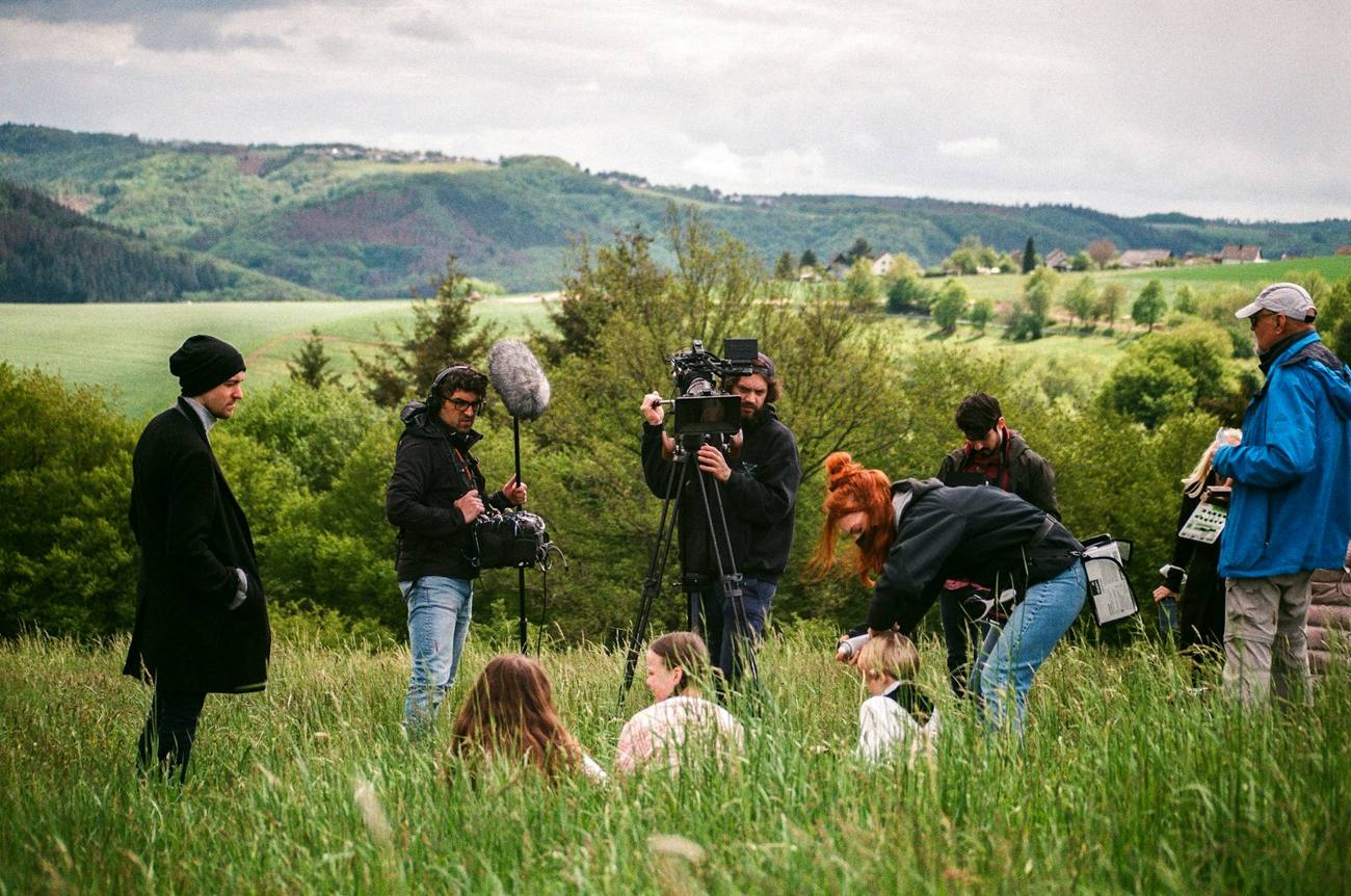 Crew filming in a green field