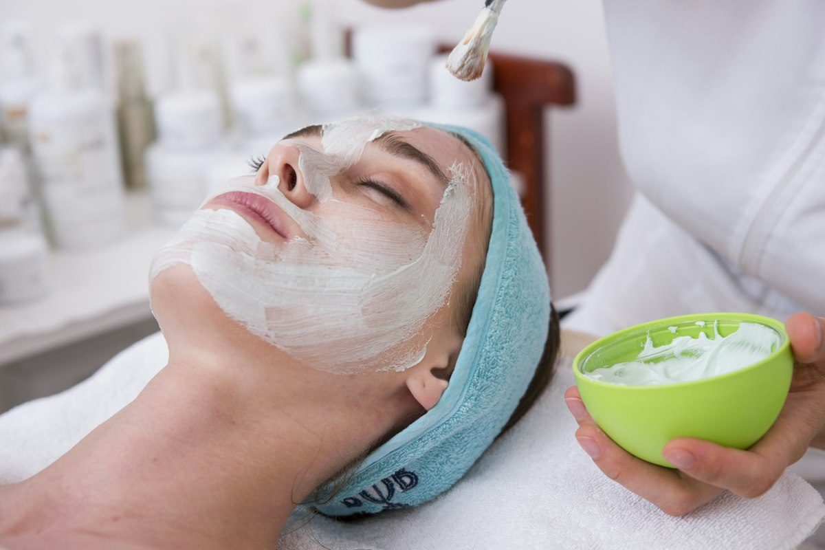 Woman lying on blue towel with white cream on face