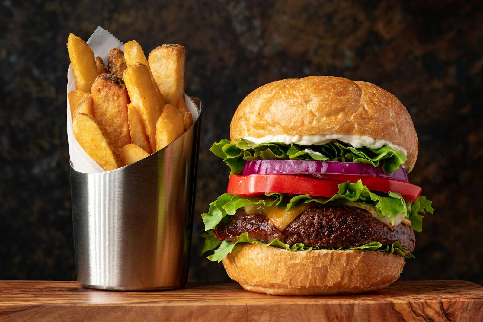 A burger served with fries in a metal cup