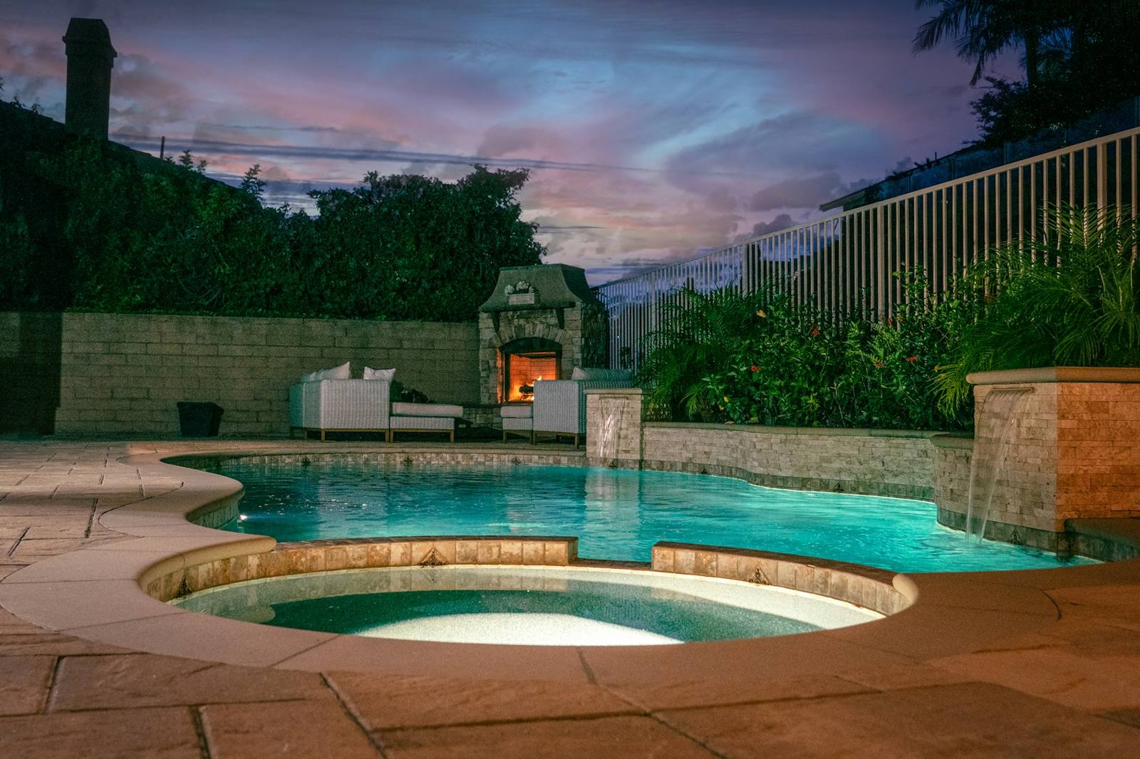 Freeform pool with spa and fire feature at dusk