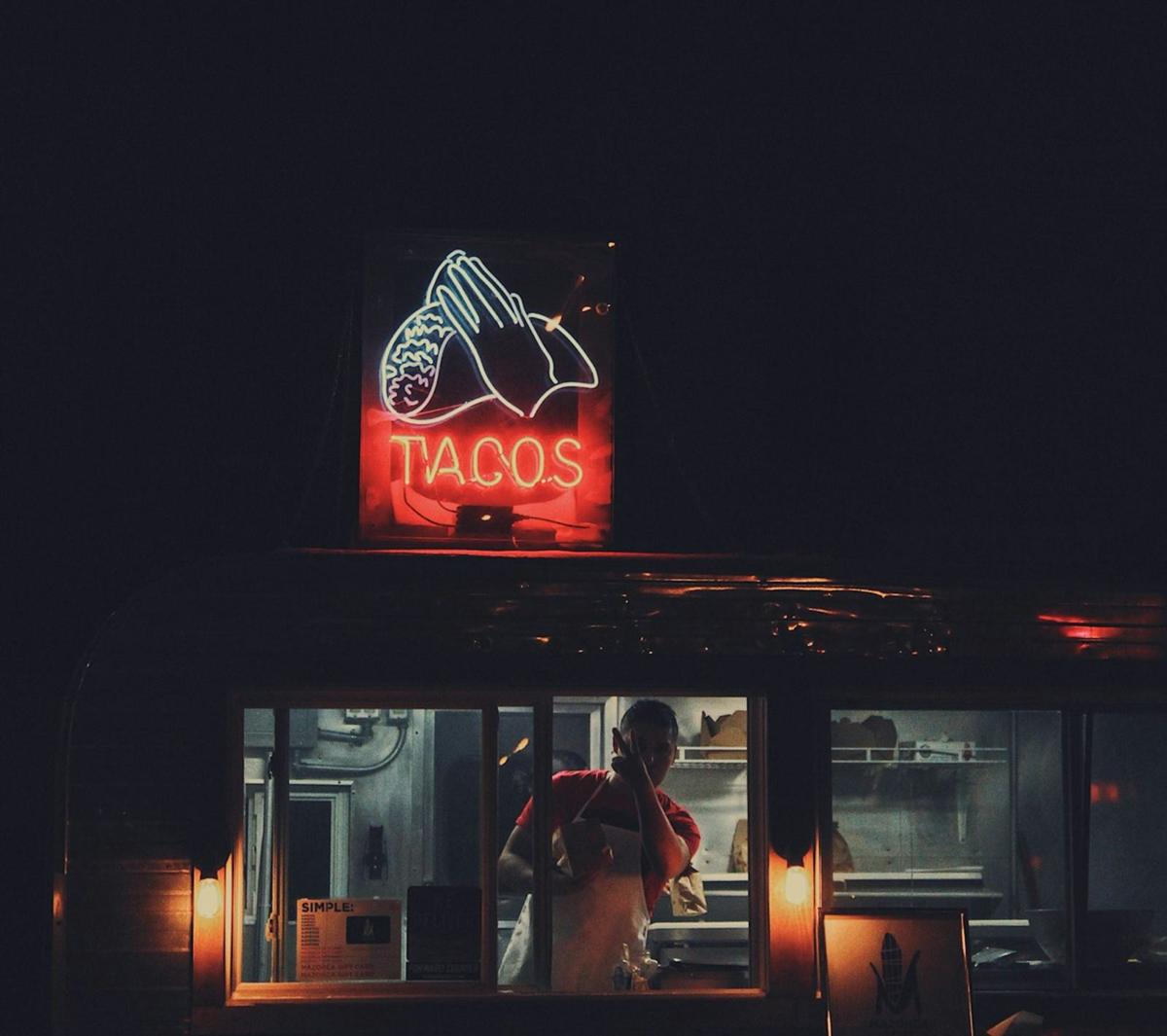 Neon taco sign over a food stall