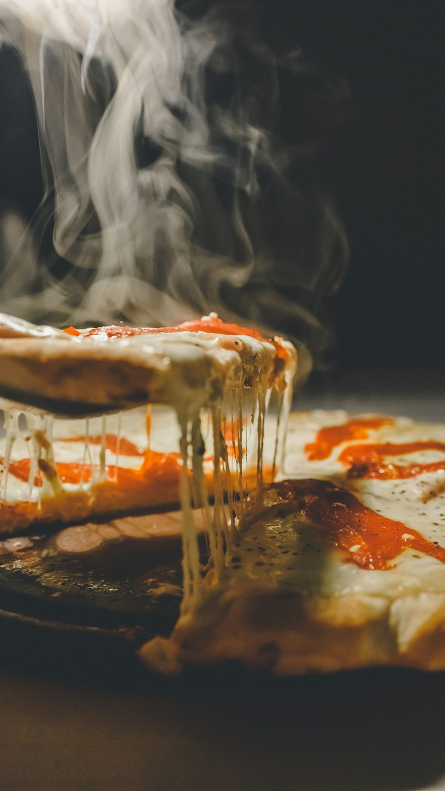 A slice being pulled from a pizza with melted cheese