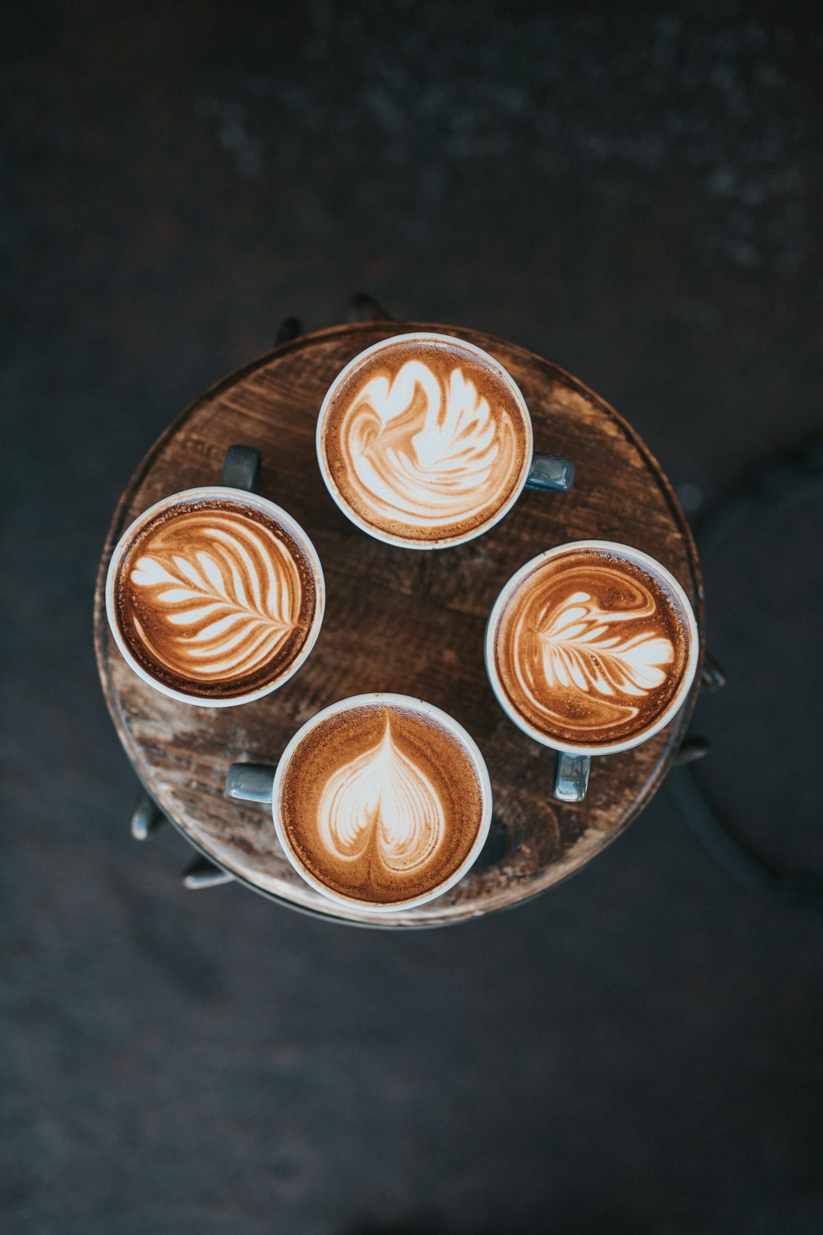Four lattes with latte art from above
