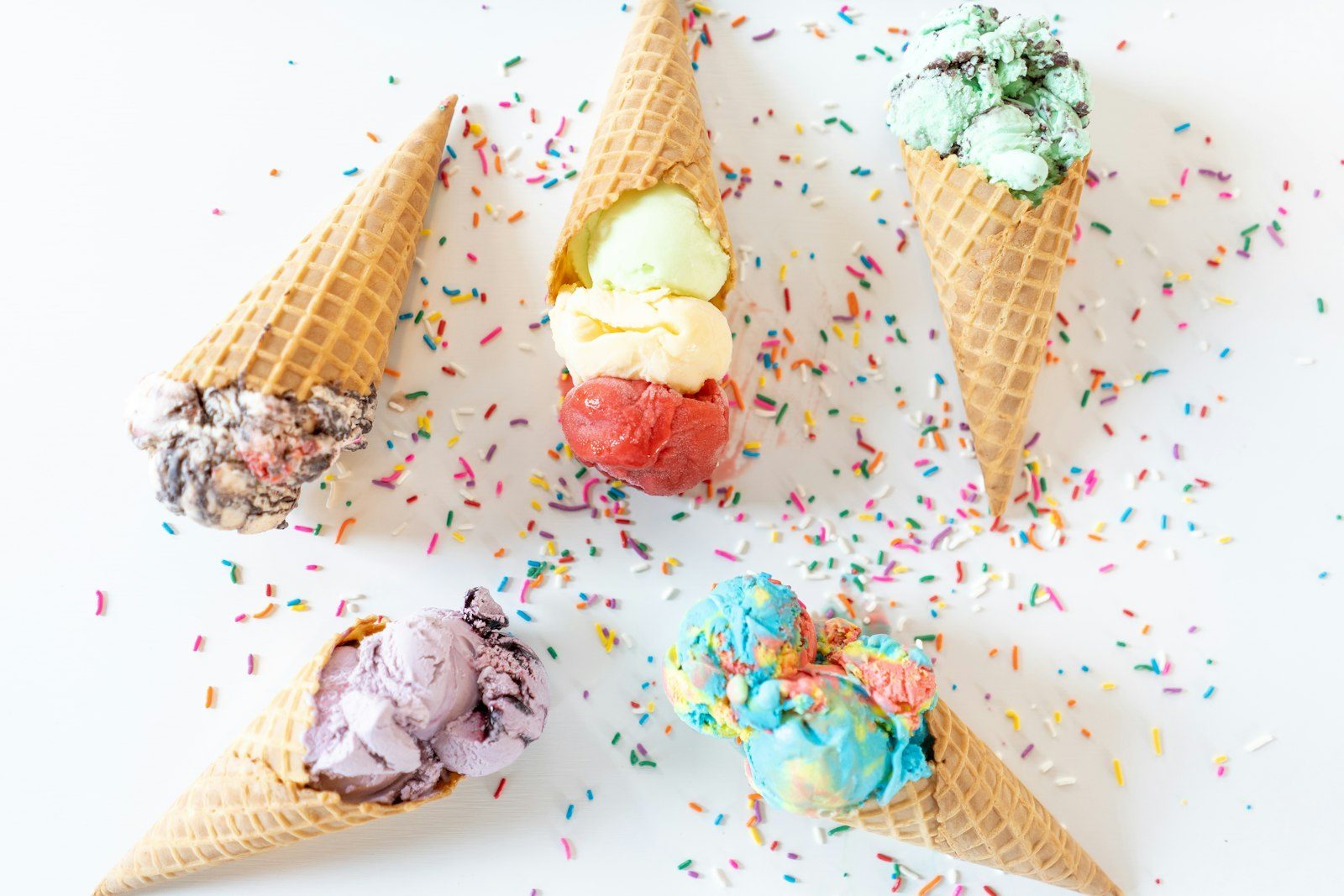 Colorful cones of ice cream on a sprinkle-covered table
