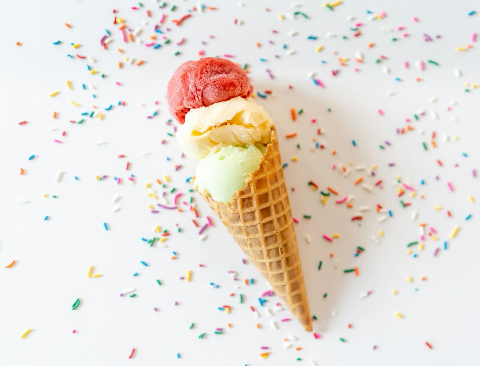 A double-scoop waffle cone surrounded by sprinkles
