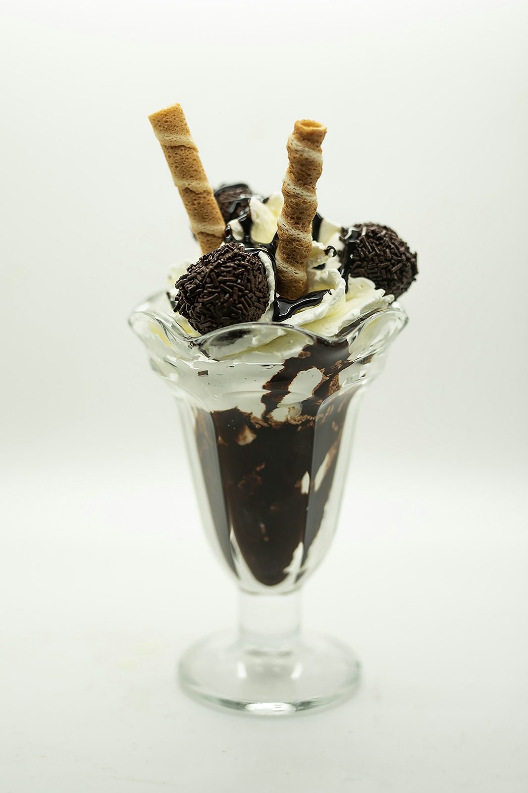 A chocolate sundae with wafer rolls and cookies