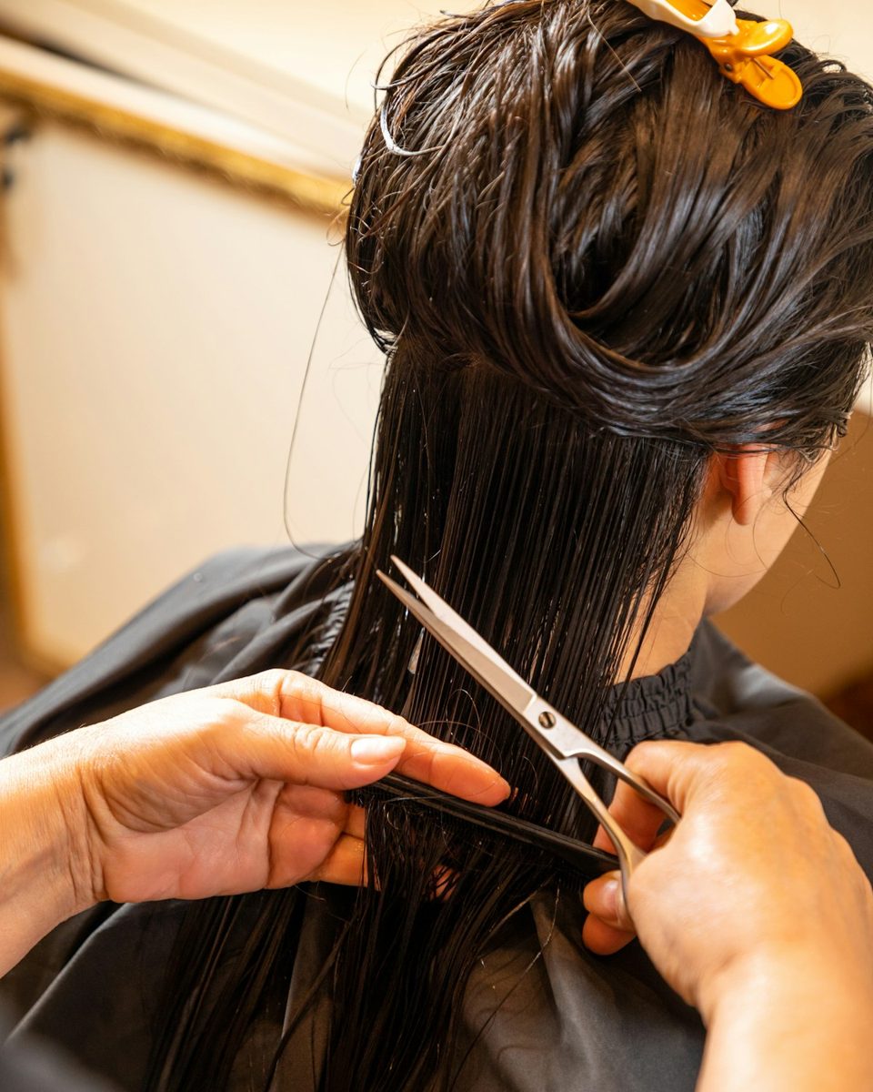A woman cutting another woman's hair with scissors