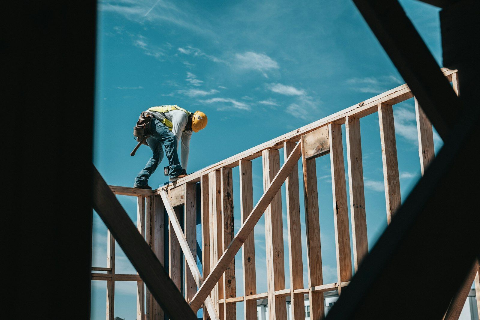 Carpenter working on a wall frame against the sky