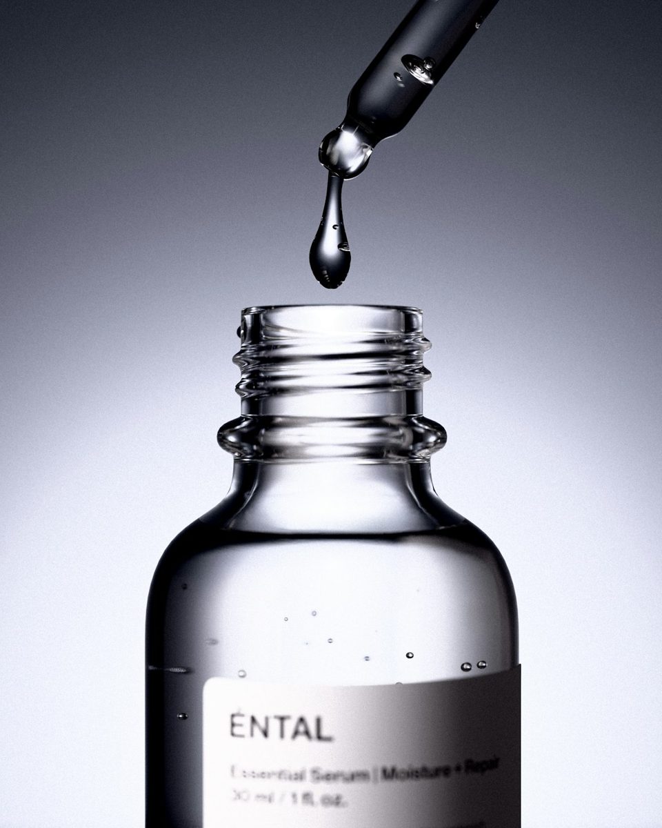 A dropper releases a drop of serum into a bottle